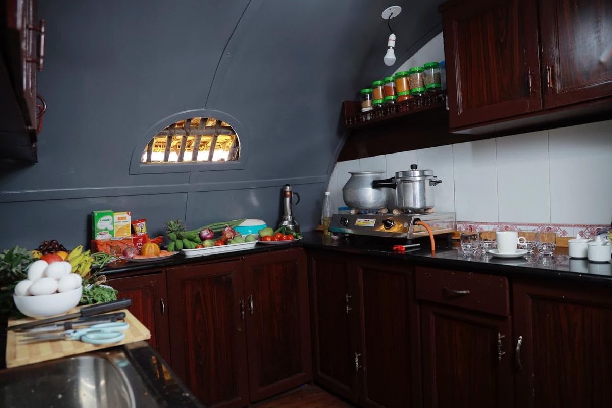 Boat kitchen with dark wooden cabinets, a gas stove, spice jars and fresh vegetables and fruit on the counter